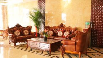 A lobby with a large, ornate sofa set, a coffee table, and a potted plant.
