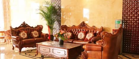 A lobby with a large, ornate sofa set, a coffee table, and a potted plant.
