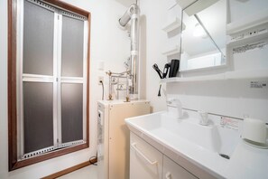 A bathroom with a white sink, a mirror, and a window with frosted glass. - GRAND SOLEIL (Sapporo)