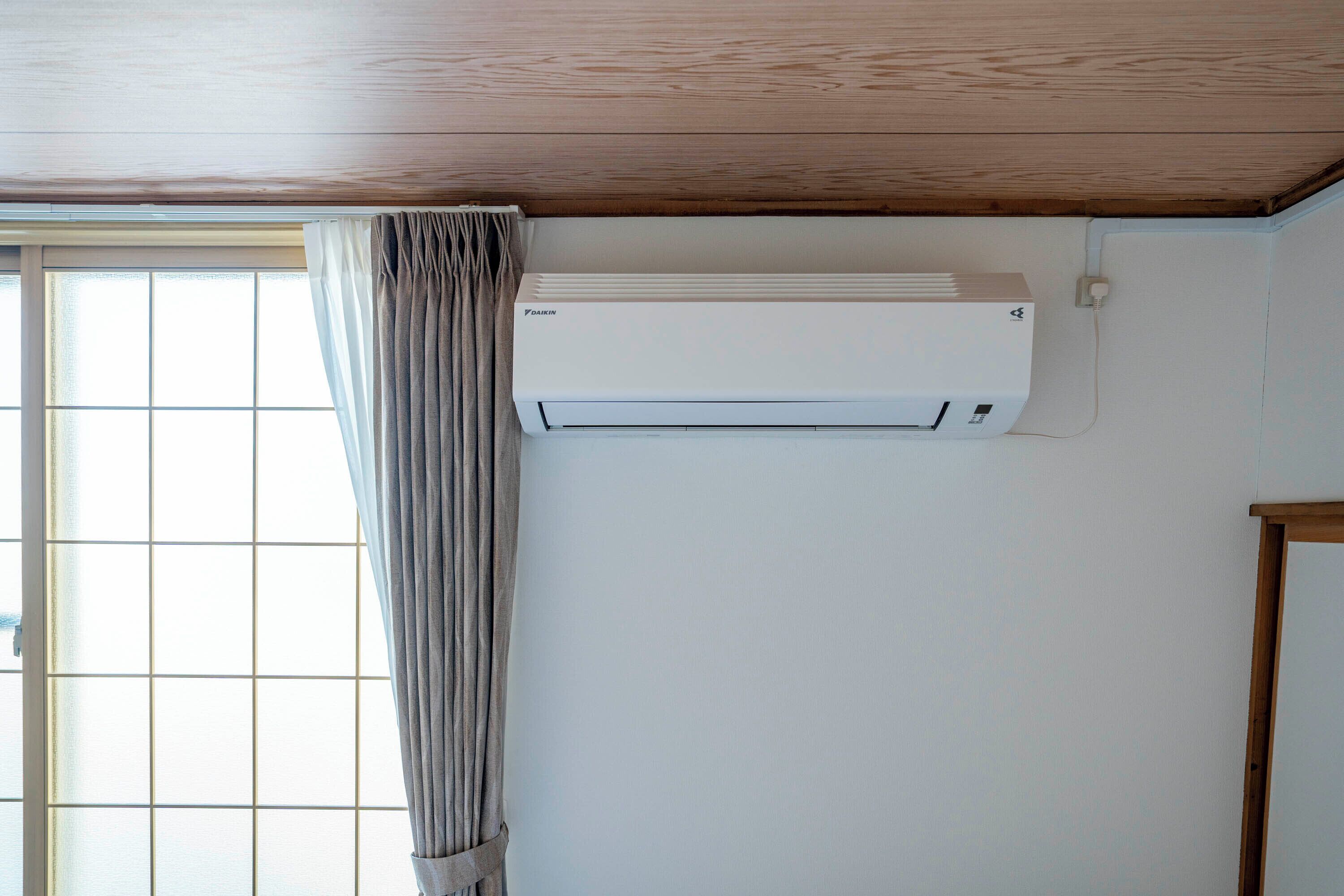 A room with a window, a curtain, and a wall-mounted air conditioner.