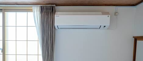 A room with a window, a curtain, and a wall-mounted air conditioner.