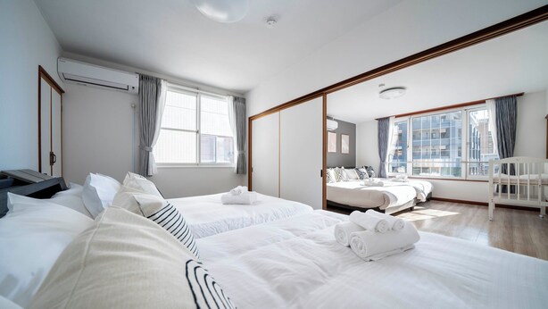 Ein Hotelzimmer mit zwei Betten, einem großen Fenster, einem Balkon und Blick auf die Stadt.