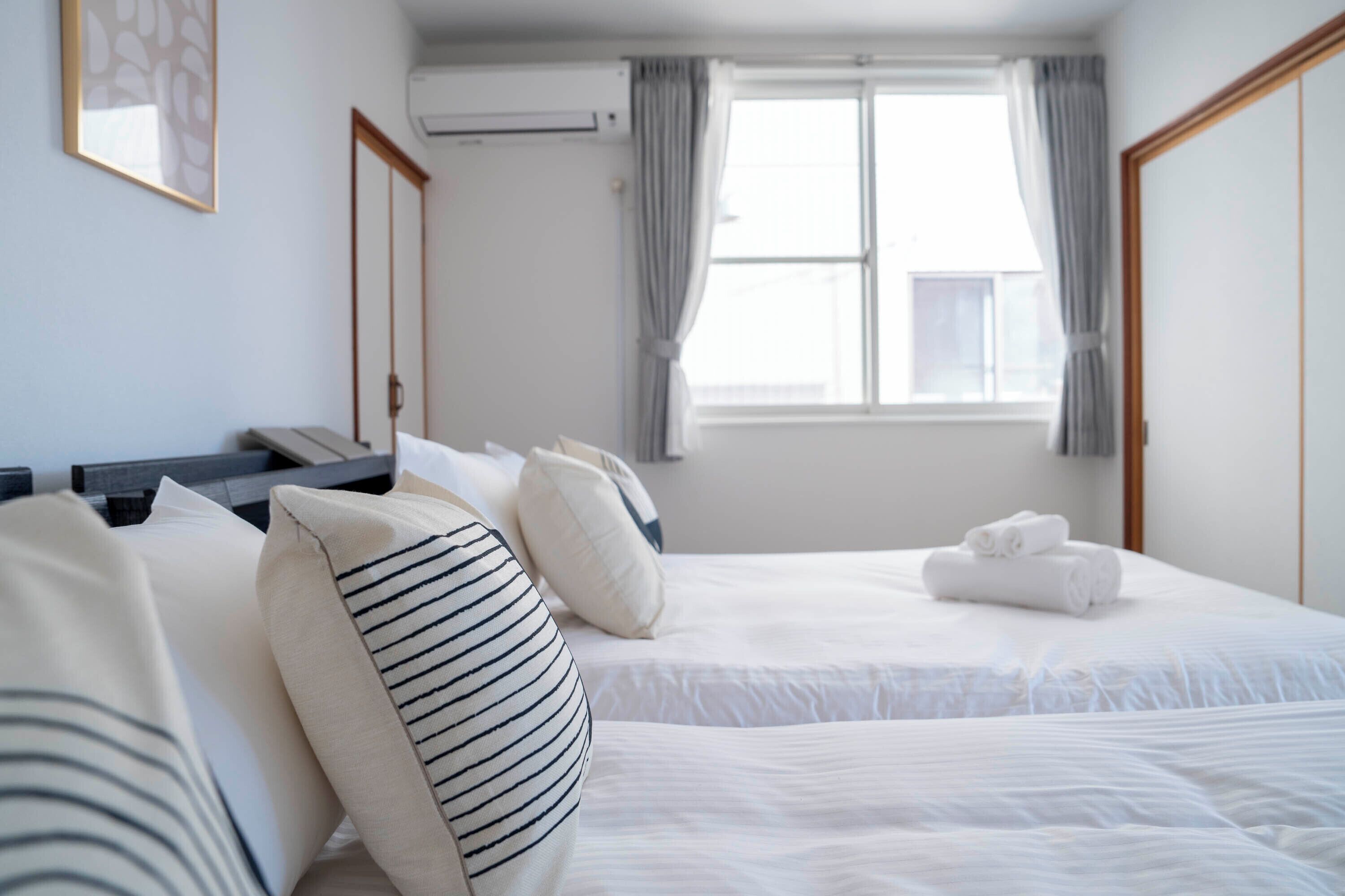 A hotel room with two beds, a desk, and a window with curtains.