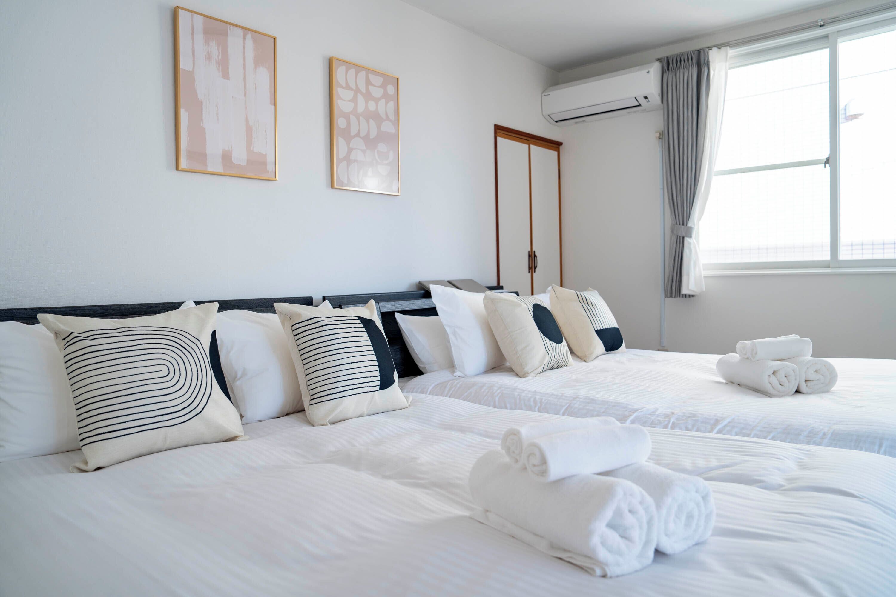 A hotel room with two beds, white bedding, and a window with curtains.