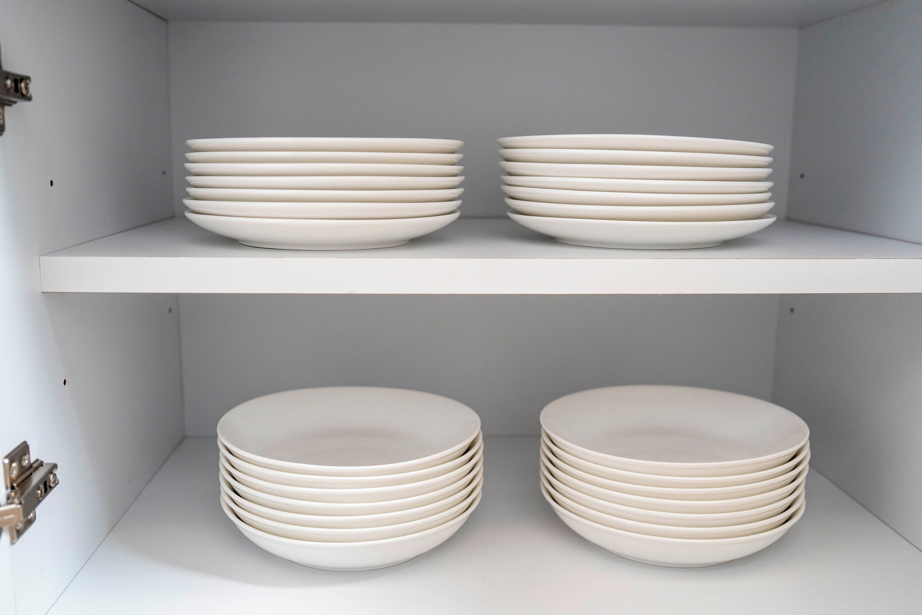 A white shelf with two stacks of white plates.