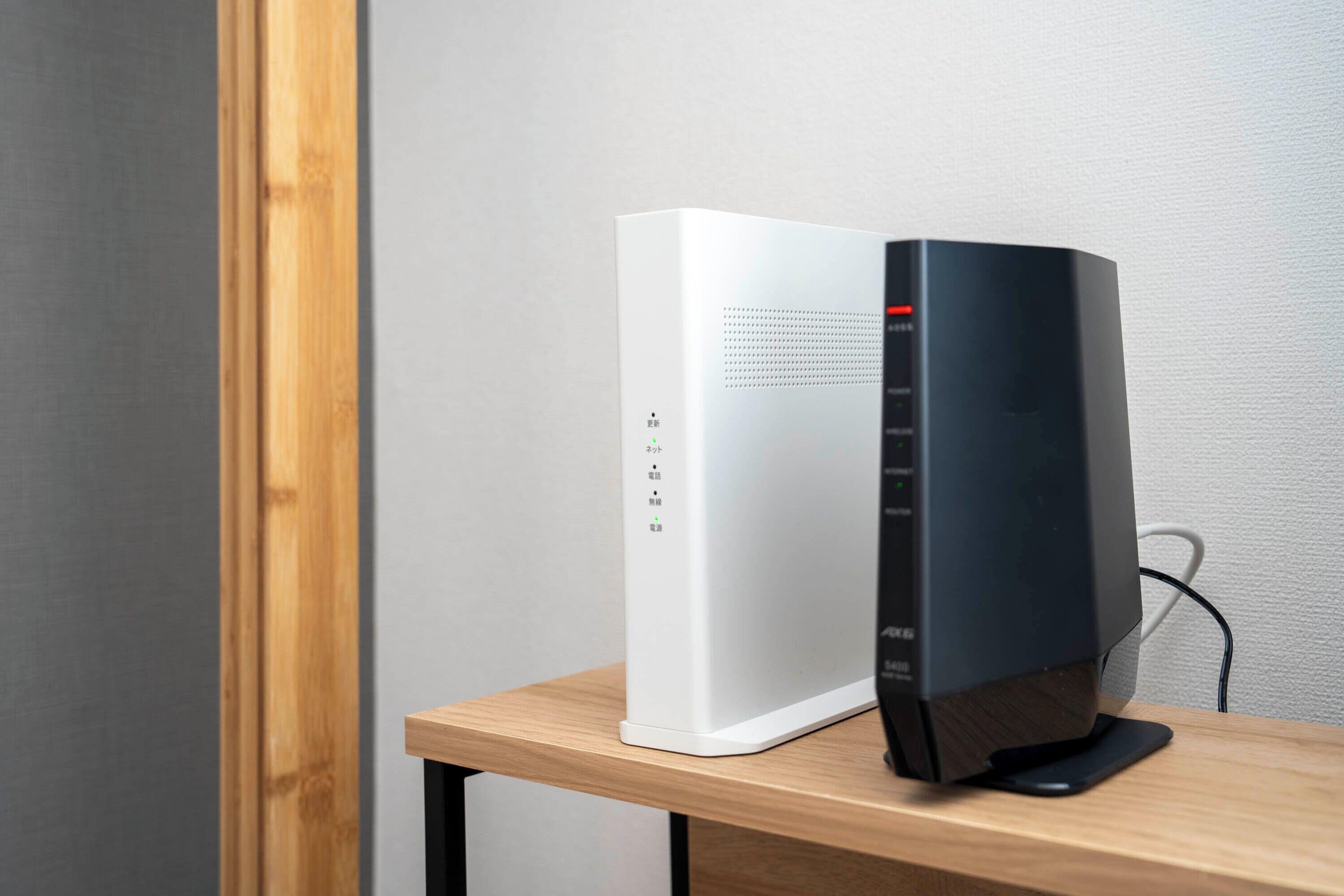 Een zwart-witte computer op een houten tafel, voor een effen muur.