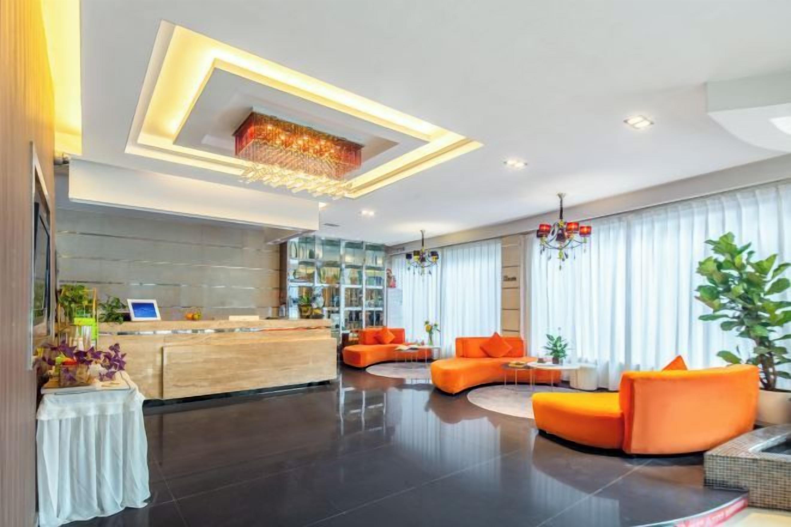 A modern hotel lobby with a reception desk, seating area, and large windows.