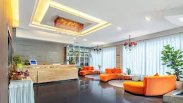 A modern hotel lobby with a reception desk, seating area, and large windows.