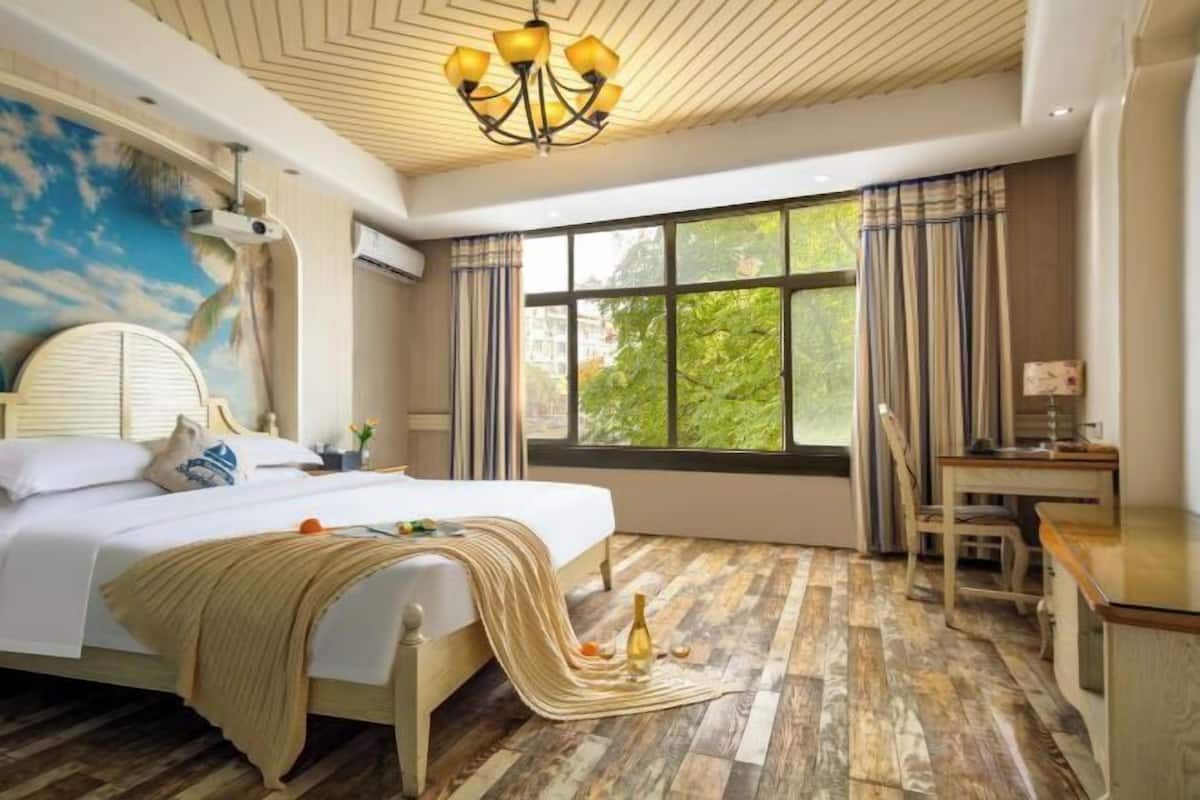 A bedroom with a bed, a desk, a chair, a window with curtains, and a ceiling with a chandelier.