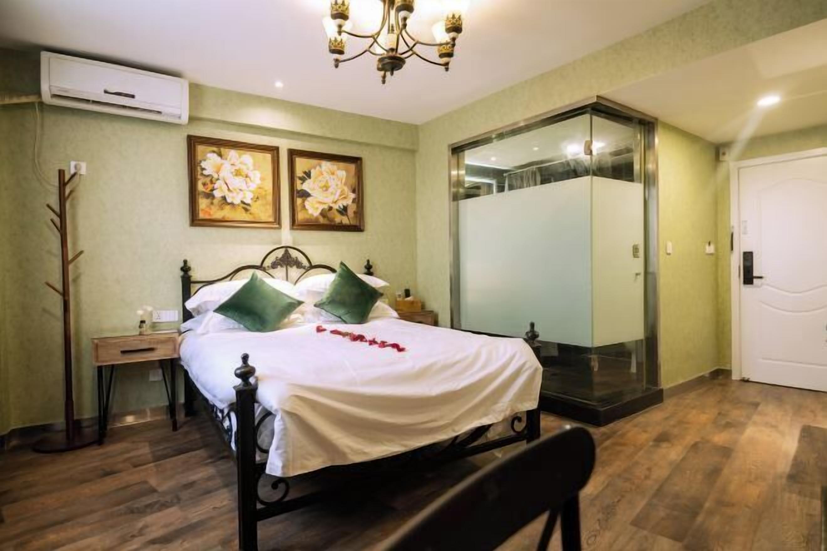 A bedroom with a bed, bedside table, wall-mounted air conditioner, and a large mirror.