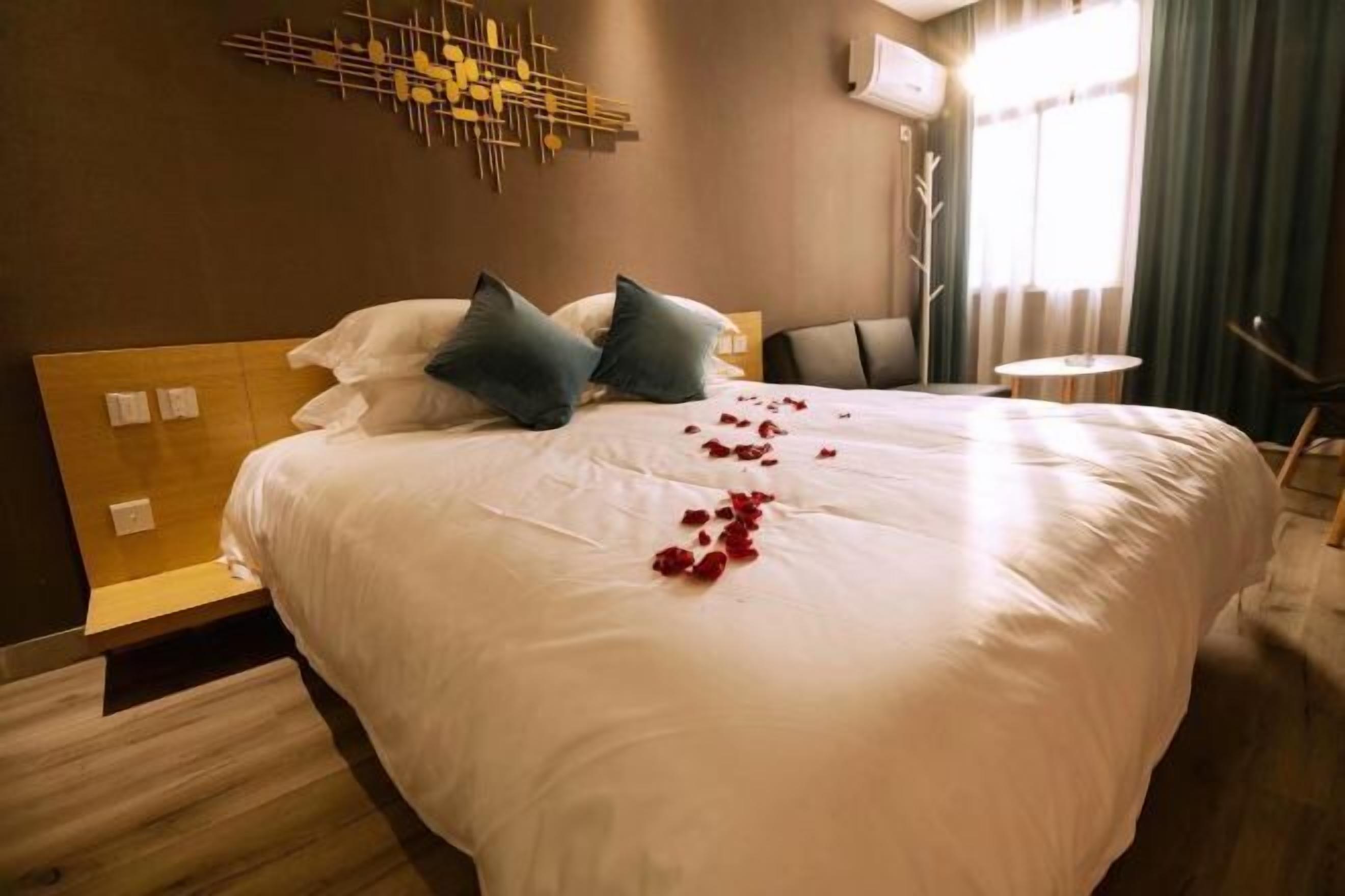 Une chambre d’hôtel avec un grand lit, une tête de lit en bois, une petite table ronde et un climatiseur fixé au mur.