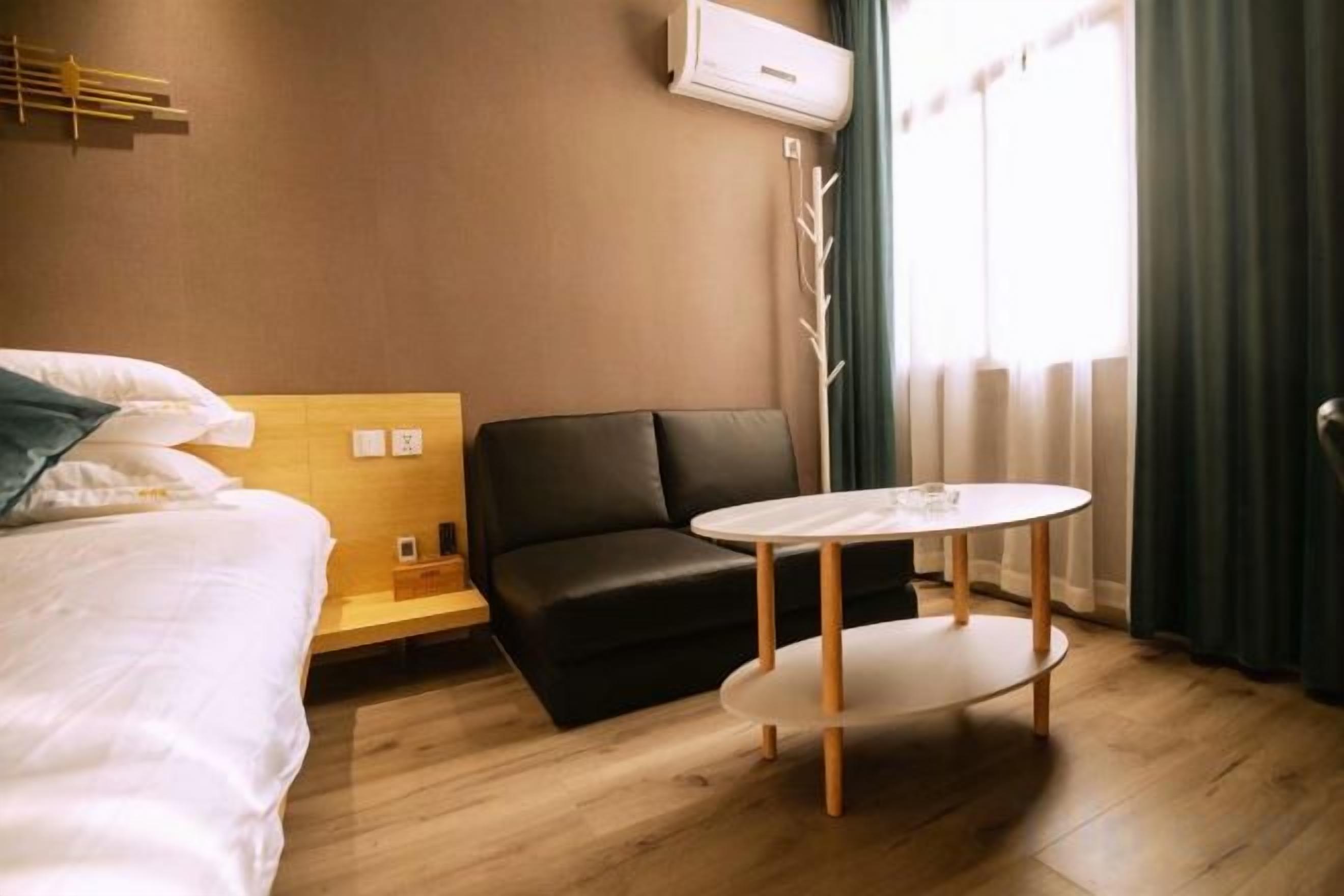 A hotel room with a bed, a sofa, a small table, and a window with curtains.