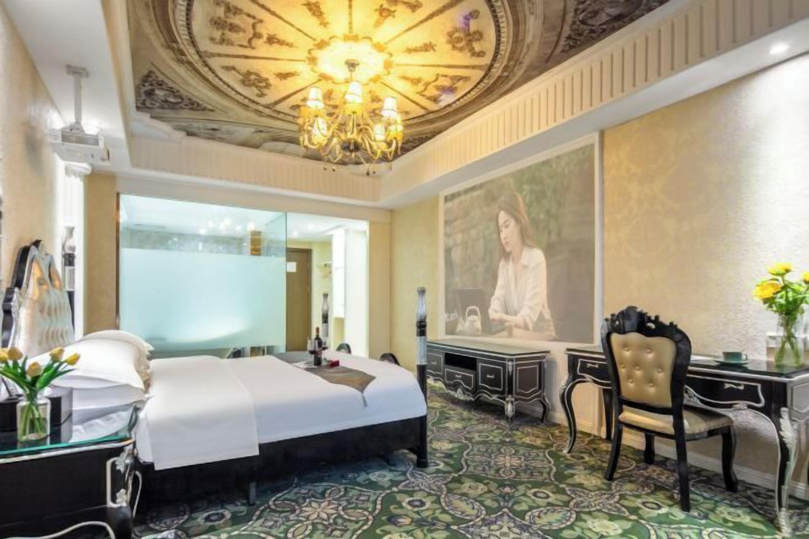 Una habitación de hotel con cama, escritorio, silla, candelabro y un cuadro grande en la pared.