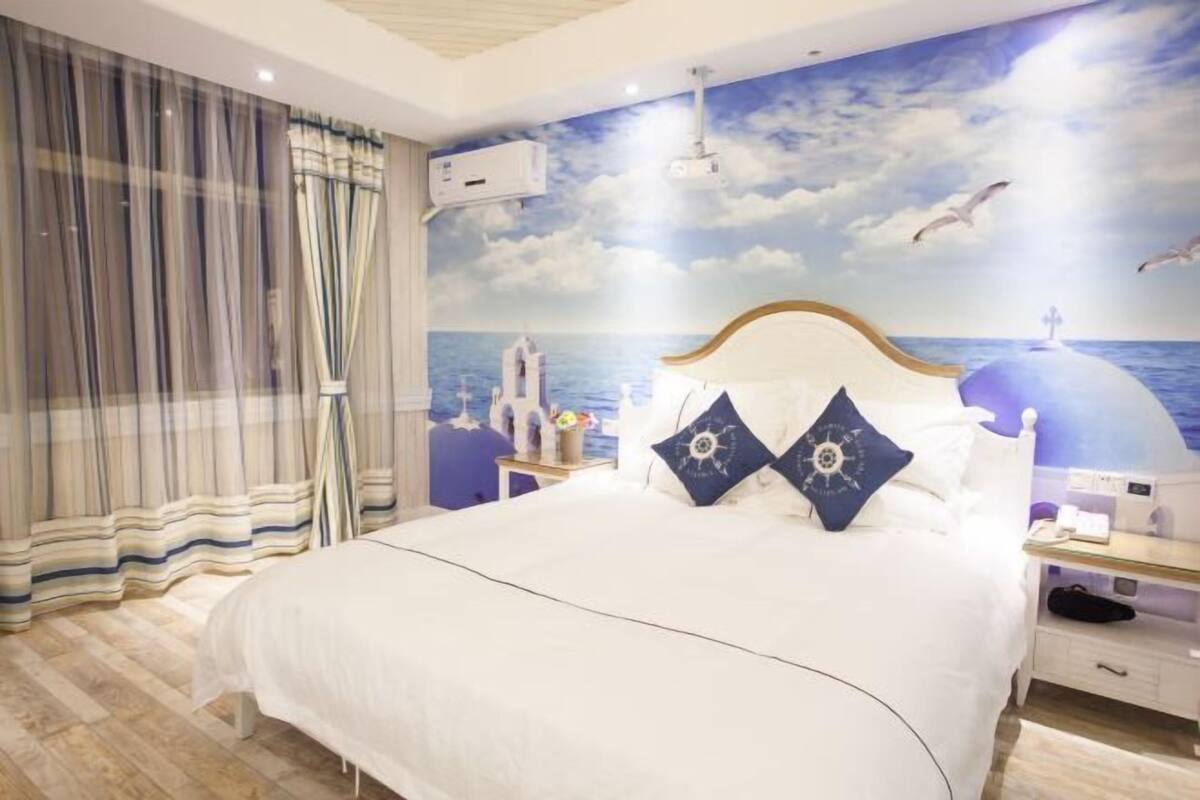 A bedroom with a bed, curtains, a nightstand, and a wall mural.