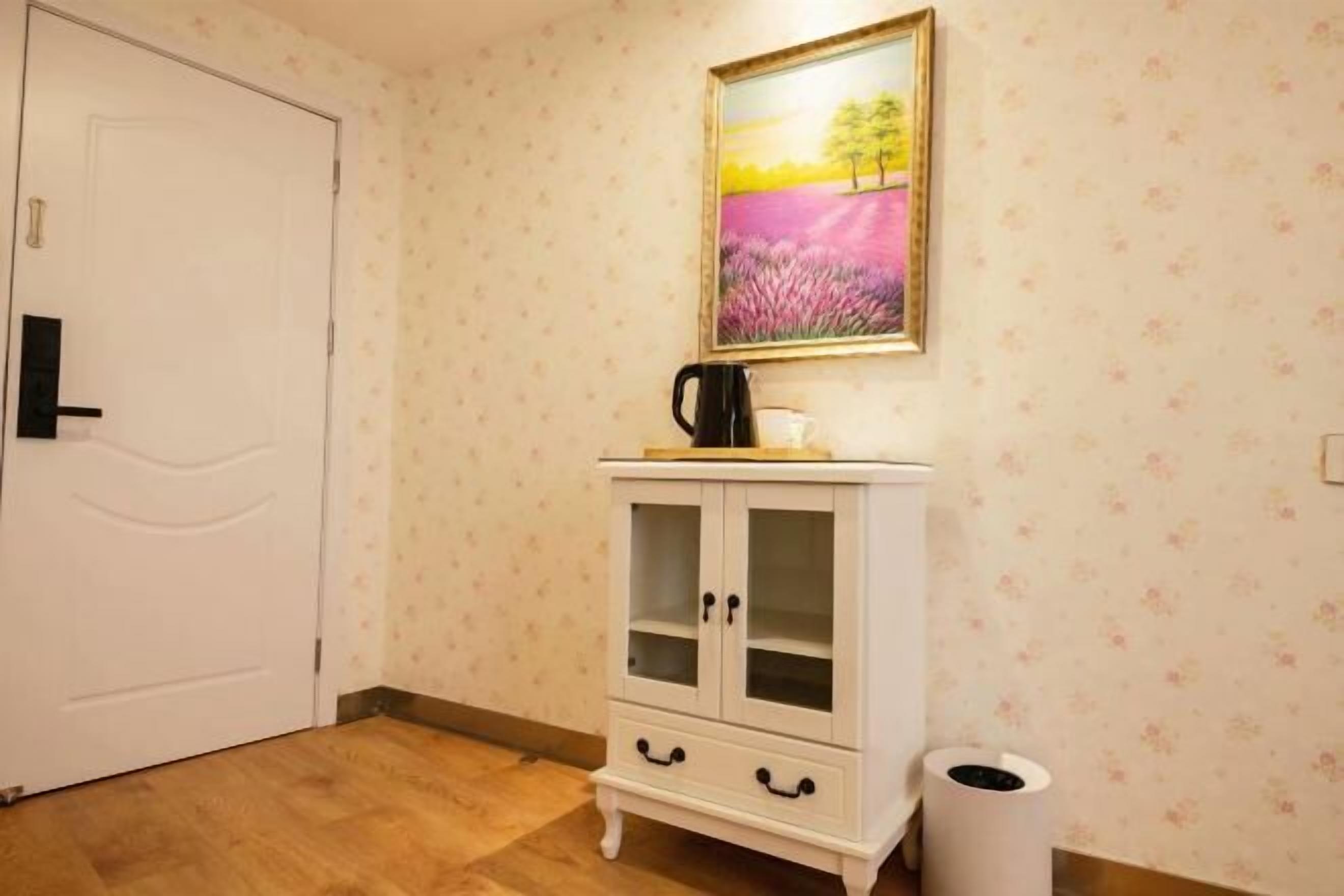 Ein Zimmer mit einer weißen Tür, einem weißen Schrank mit Glastüren, einem gerahmten Bild an der Wand und einem Mülleimer.