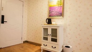 A room with a white door, a white cabinet with glass doors, a framed painting on the wall, and a trash bin. - Xianju Nanxingyuan Boutique Hotel (Wuyue Plaza) (Xianju)