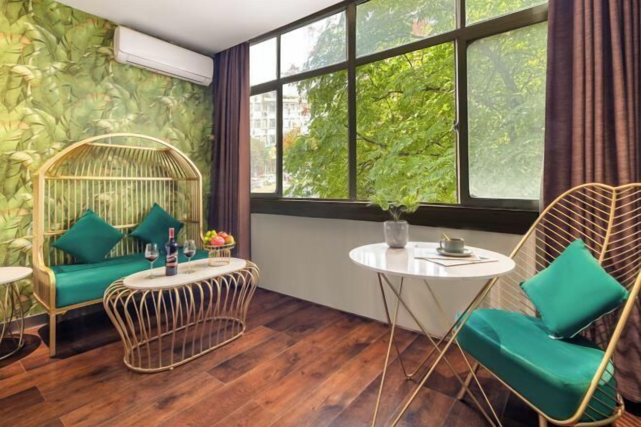 Ein Zimmer mit großem Fenster, einem runden Tisch, zwei Stühlen und einer kleinen Couch.