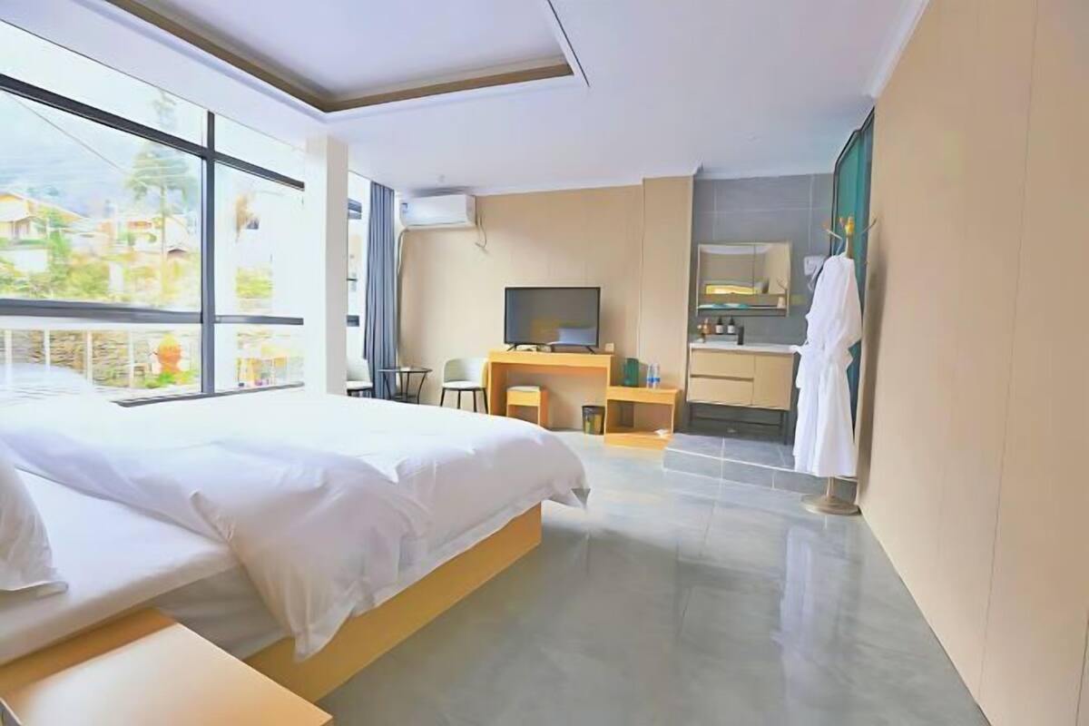 Ein Hotelzimmer mit Bett, Schreibtisch, Fernseher und Bad.