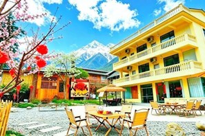 A hotel with outdoor seating, a mountain view, and a traditional wooden building.