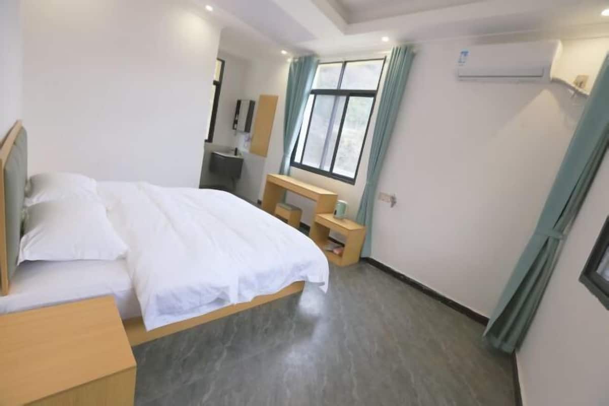 Un dormitorio con cama, escritorio, silla y ventana con cortinas.
