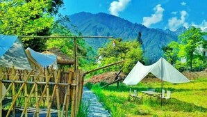 A bamboo gate leading to a tented area with a river path. - Yunong Hot Spring Courtyard Homestay (Hailuogou Glacier Forest Park Branch) (Luding)