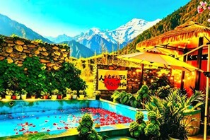 Una piscina con nenúfares, un muro de piedra y montañas al fondo.