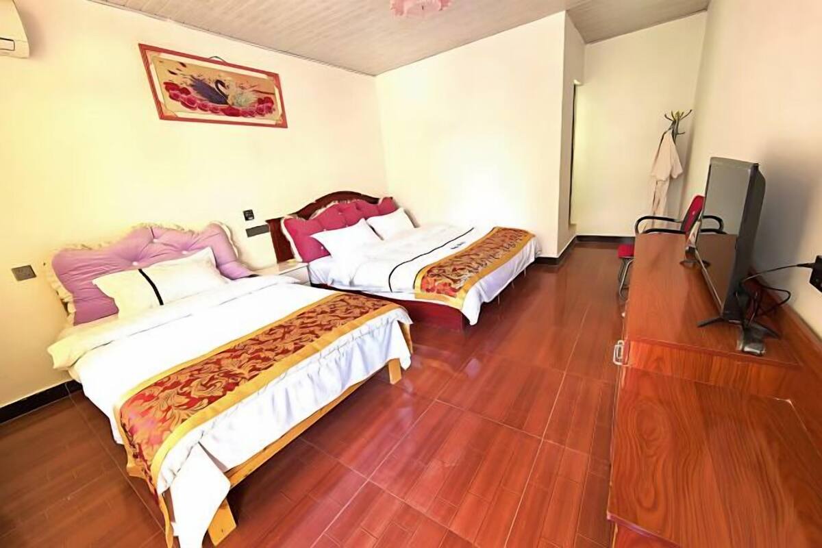 Ein Hotelzimmer mit zwei Betten, einem Holzschrank, einem Fernseher und einem Bild an der Wand.
