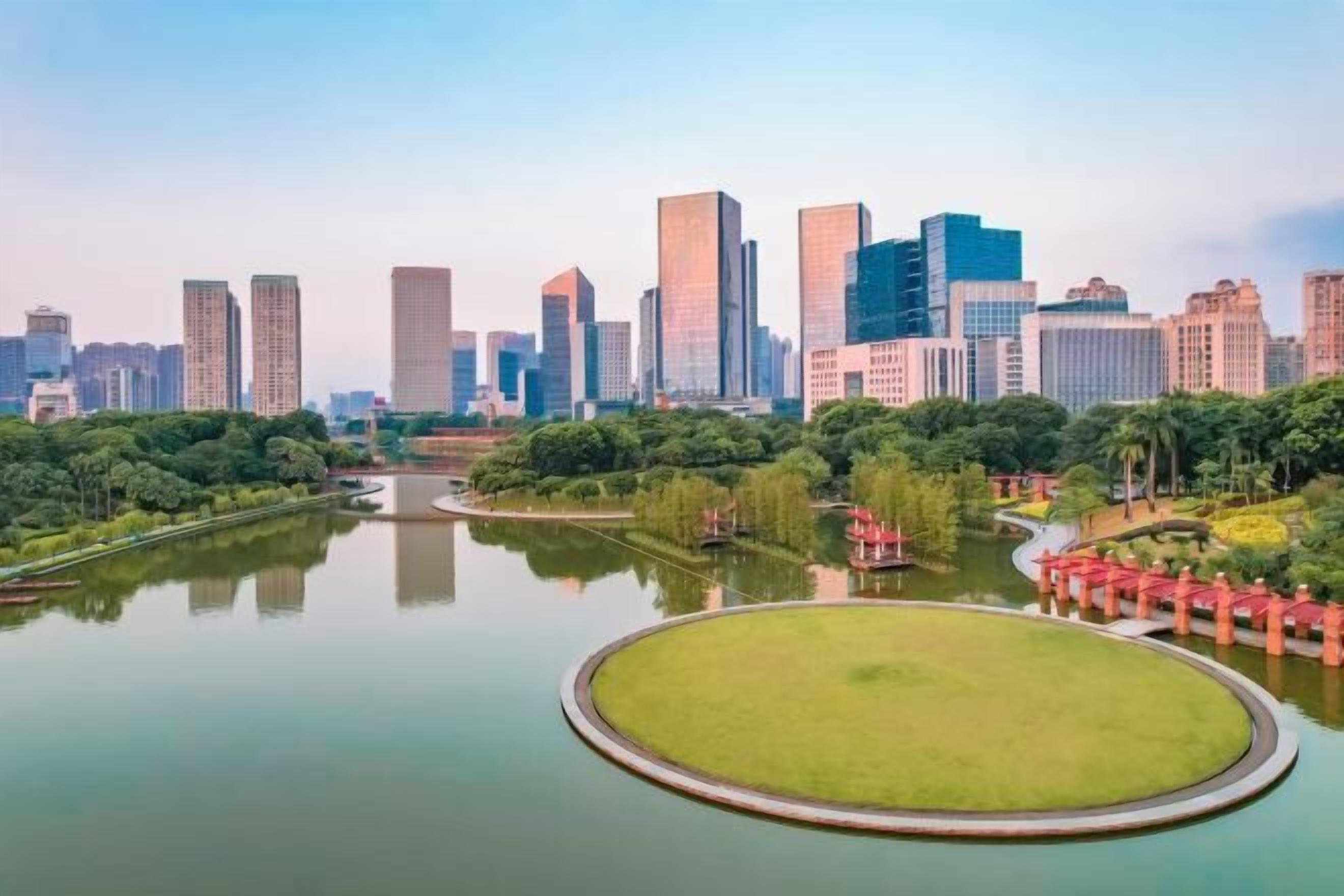 A cityscape with modern high-rise buildings and a central circular park with a pond.
