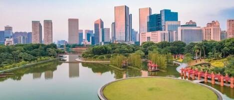 A cityscape with modern high-rise buildings and a central circular park with a pond.