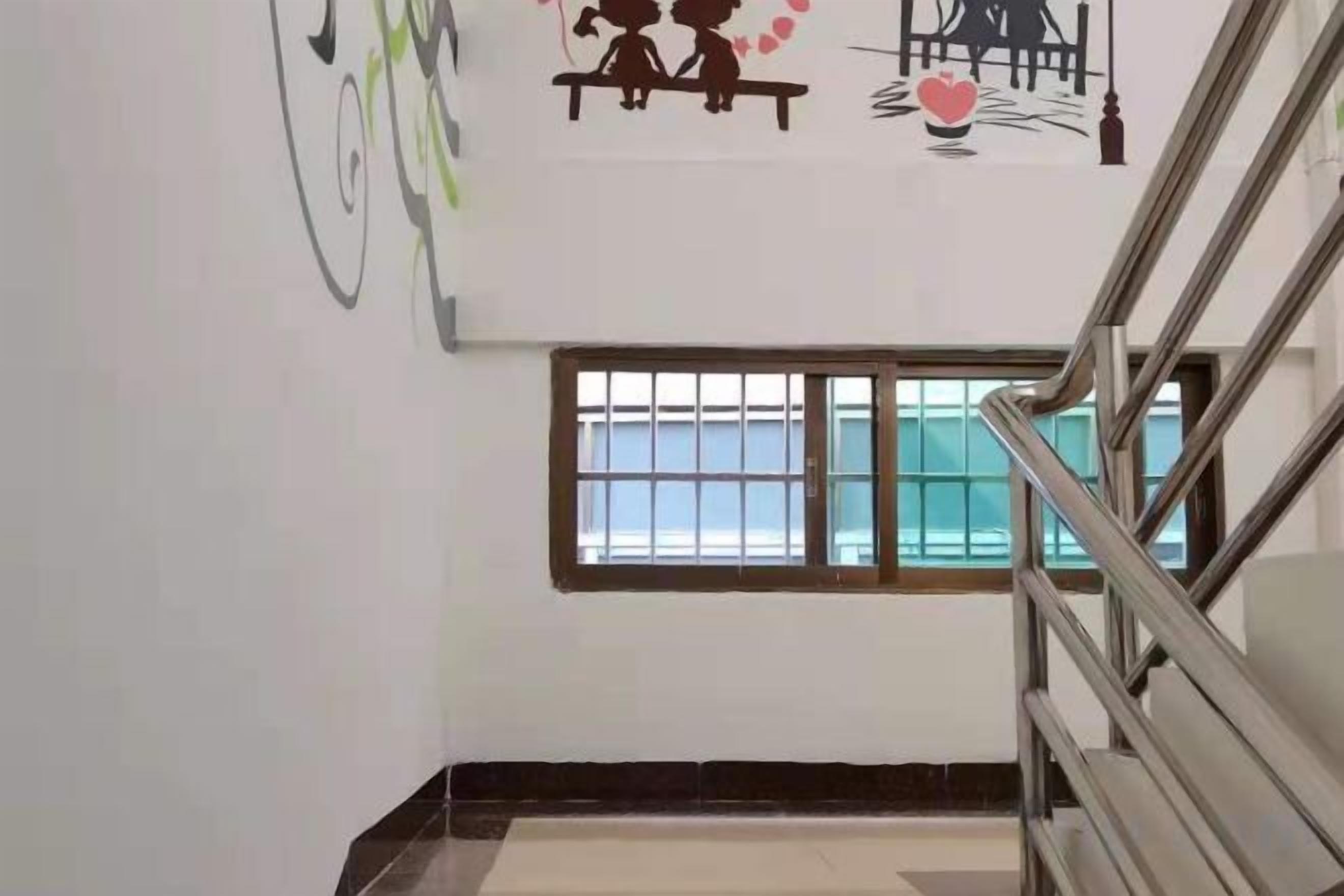A staircase with metal railings, a window with bars, and a wall with a simple graphic.