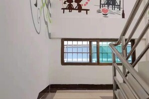 Una escalera con barandales de metal, una ventana con barrotes y una pared con un gráfico sencillo.