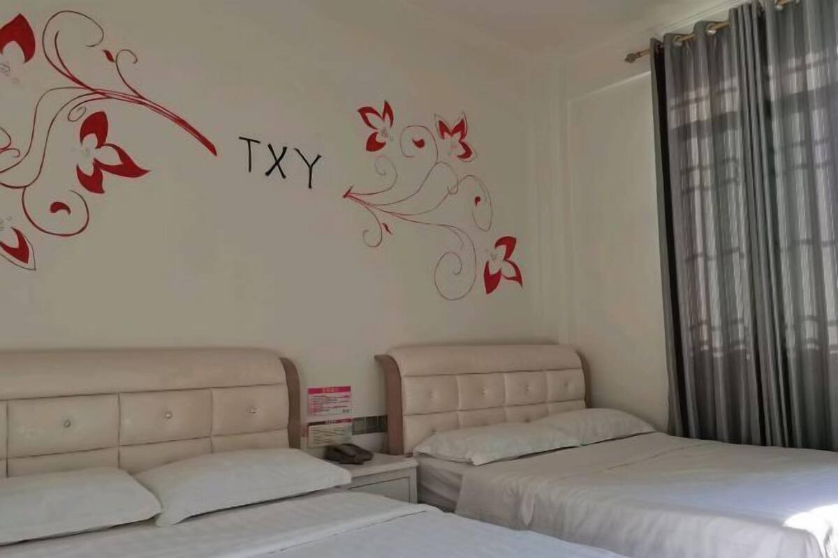 Ein Hotelzimmer mit zwei Betten, einer Wand mit floralem Dekor und einem Vorhang.