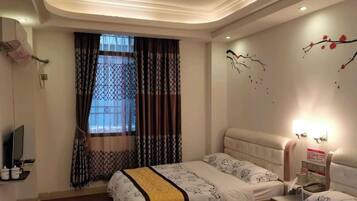 A hotel room with a bed, bedside table, and a window with curtains.