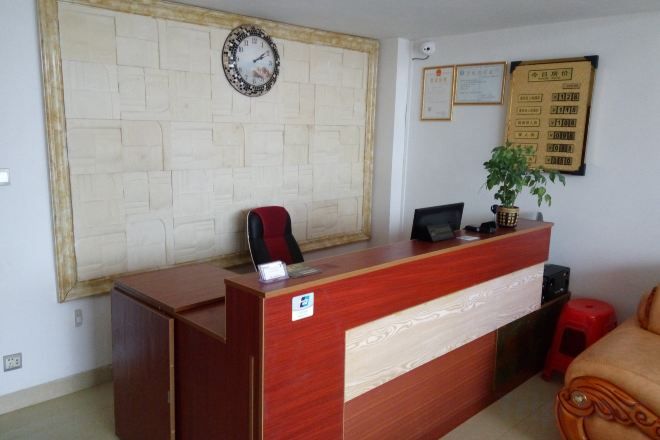 A reception desk with a clock, a framed certificate, and a potted plant.