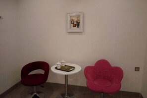 A room with two chairs, one red and one pink, and a small table with a tray and two containers. - Nanxiong Huangkeng Town Minyi Tourism Accommodation (Nanxiong)