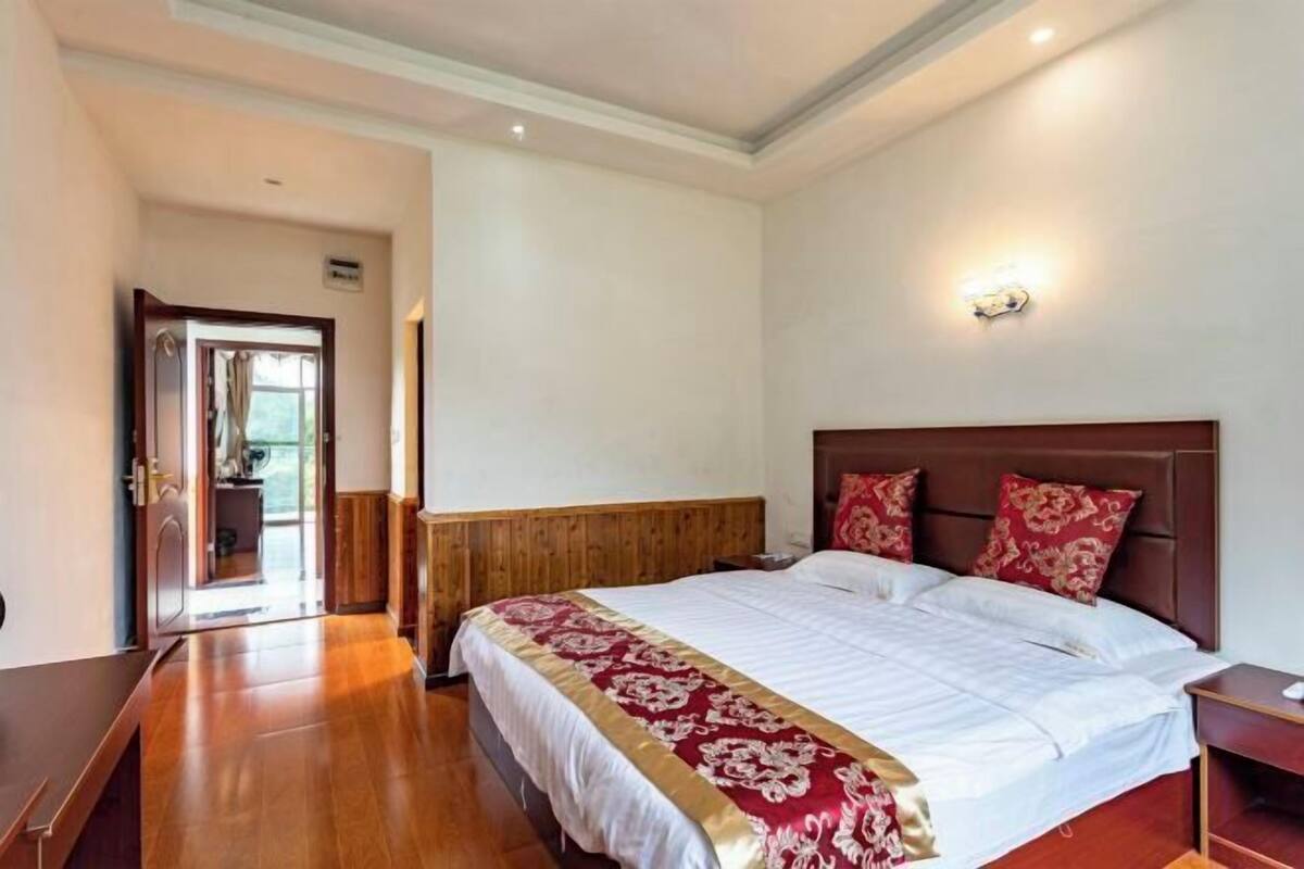 Quarto de hotel com cama de madeira, mesa de cabeceira e porta para um banheiro.