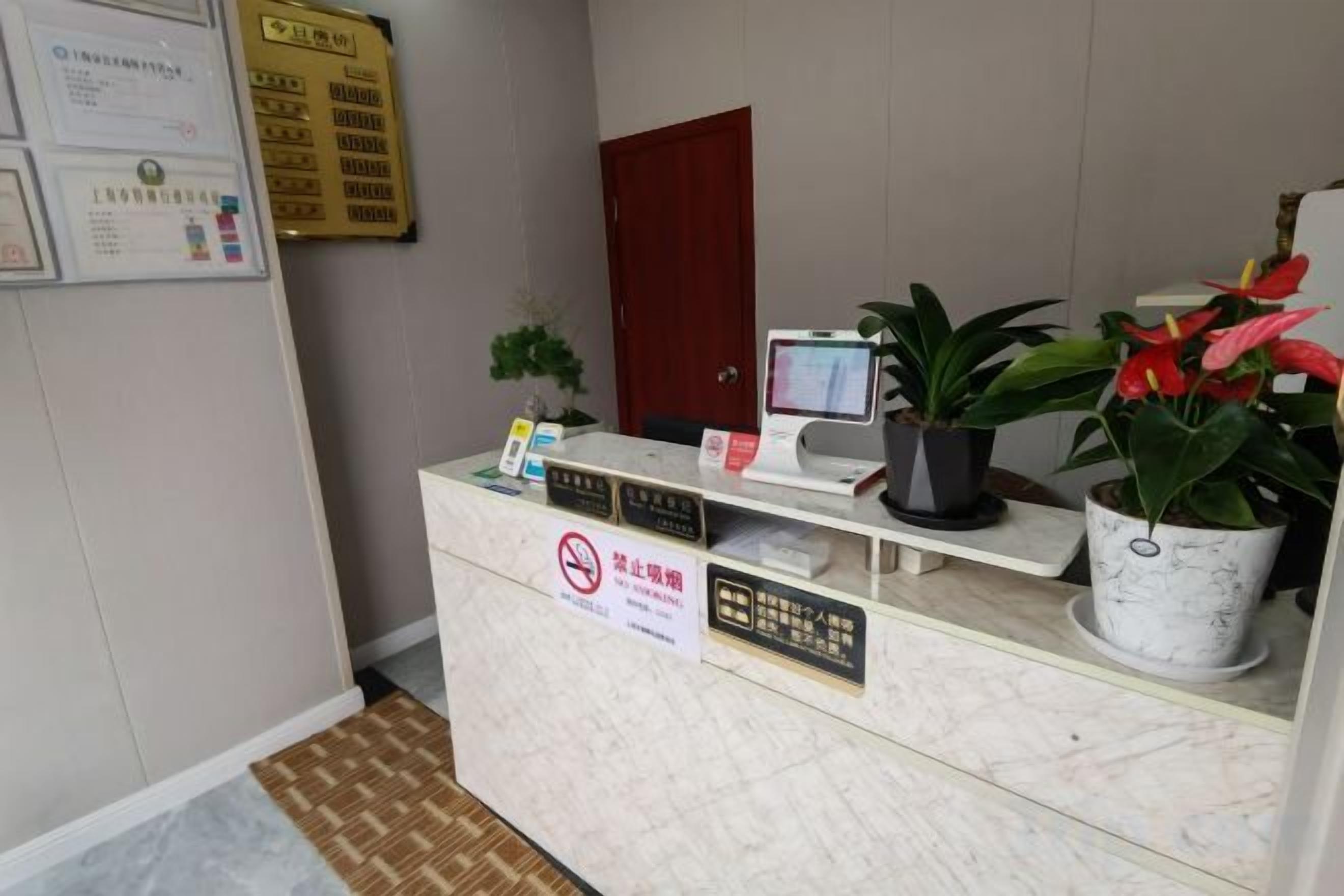 A reception desk with a computer monitor, a telephone, and a sign prohibiting smoking.