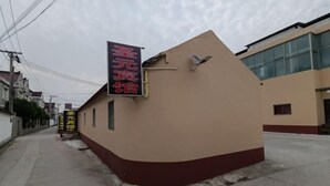 Un edificio con fachada color crema y base roja, que presenta un letrero con caracteres chinos.