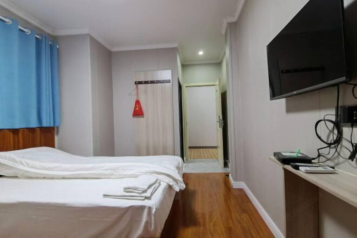 A hotel room with a bed, a TV mounted on the wall, and a desk with a computer.