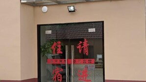 Entrada de hotel con puerta de vidrio y señalización roja.