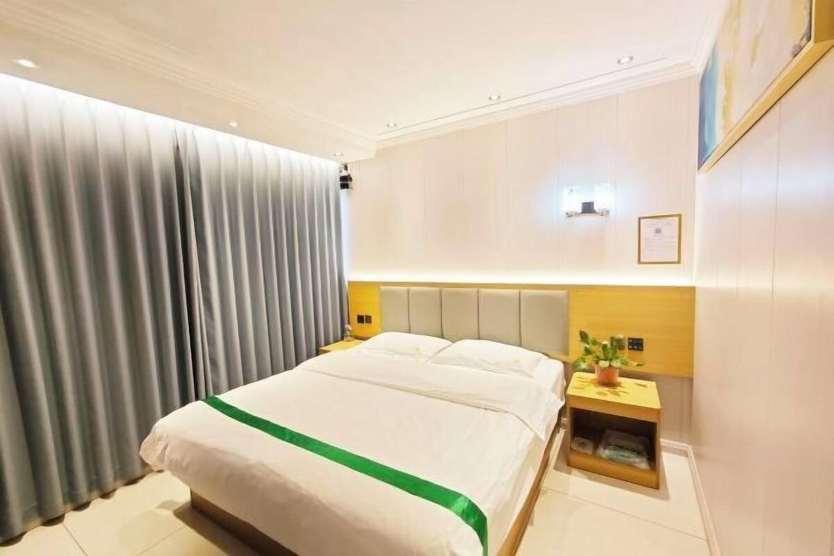 A hotel room with a large bed, a nightstand with a lamp, and a wall-mounted light fixture.