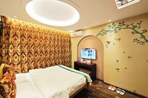 A hotel room with a bed, a television on a stand, and a wall with a tree decal. - Waltz Hotel (Huaibei)