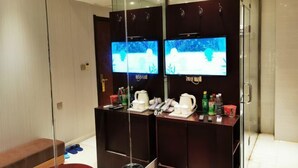 A modern bathroom with a glass partition, a bench, a sink with a mirror, and two televisions on the wall. - Waltz Hotel (Huaibei)