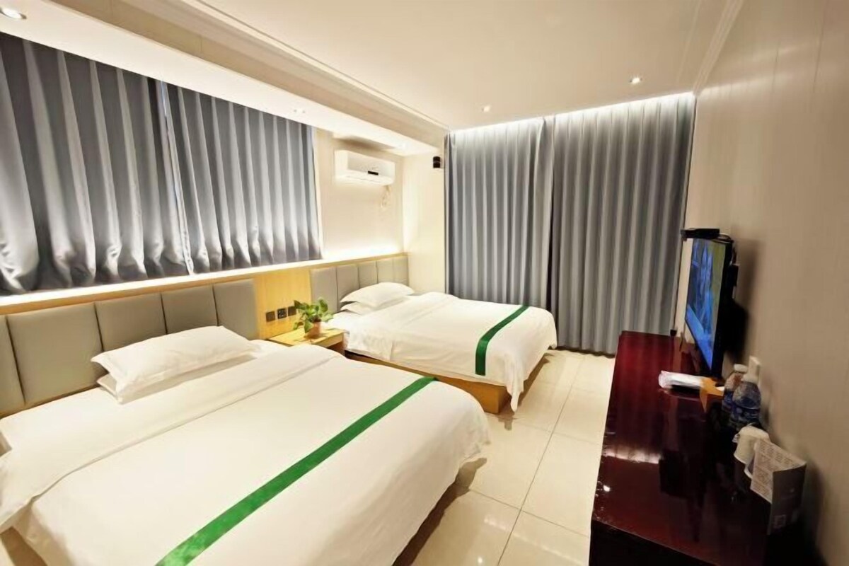 A hotel room with two beds, a desk, a TV, and curtains.