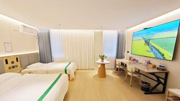 A hotel room with two beds, a desk, a TV, and a window with curtains. - Waltz Hotel (Huaibei)