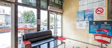 A reception area with a black sofa, a red chair, and a glass table.