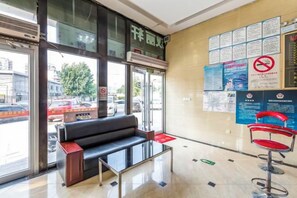 Un área de recepción con un sofá negro, un sillón rojo y una mesa de vidrio.