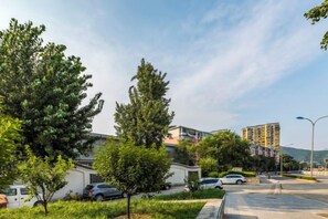 A residential area with trees, parked cars, and a building in the background. - Kunbo Traders Hotel (Beijing)