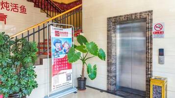 A hotel lobby with a staircase, an elevator, and a signboard.