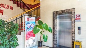 Eine Hotelhalle mit Treppe, Aufzug, Rauchverbot-Schild und einer Zimmerpflanze.